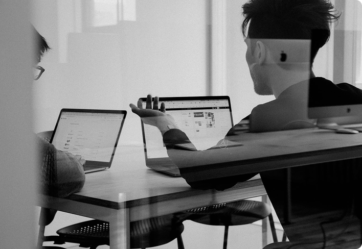 Two people working on laptops at a shared desk