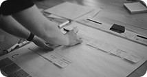 Hands arranging sticky notes and wireframes on a desk