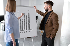 Two coworkers reviewing chart on whiteboard