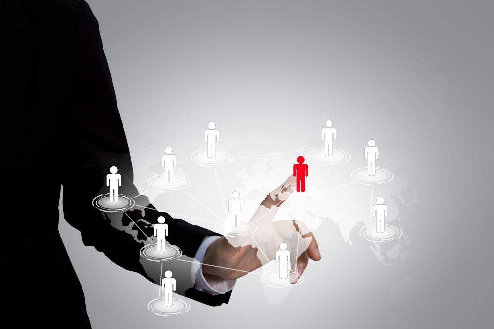 Hand selecting one highlighted figure from a network of people, representing qualified local leads